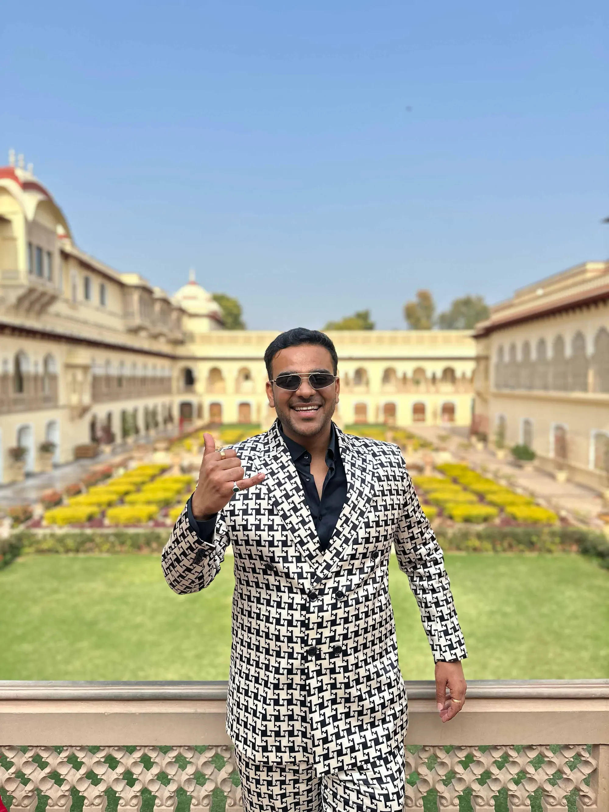 Chirag Vithalani in a houndstooth suit in the gardens of Rambagh Palace, Jaipur